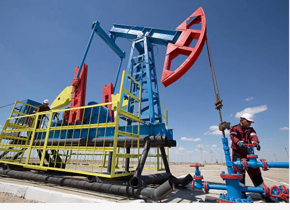Workers at a colorful oil pumpjack in the field